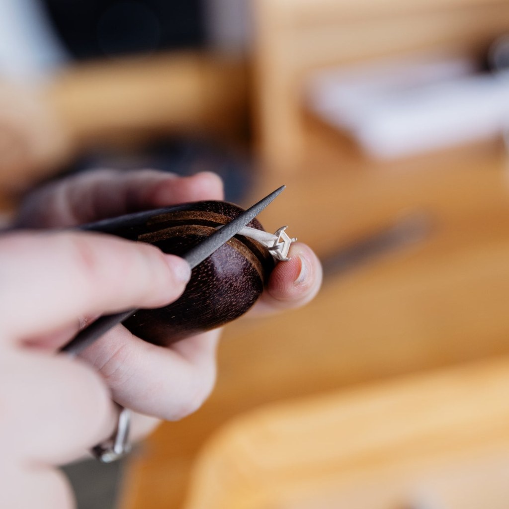 Manos del orfebre trabajando un anillo de oro